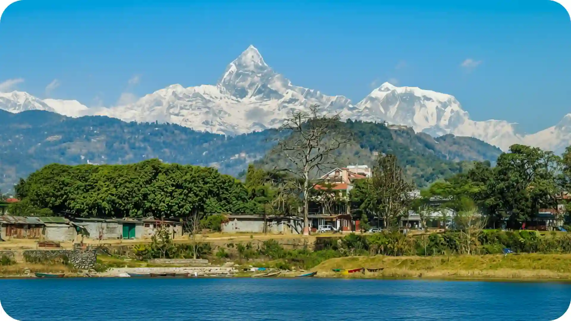 Machapuchare Fishtail mountain at sunrise towering over Pokhara Valley in Nepal with glowing Himalayan peaks and clear sky – Ghumora scenic mountain view experience